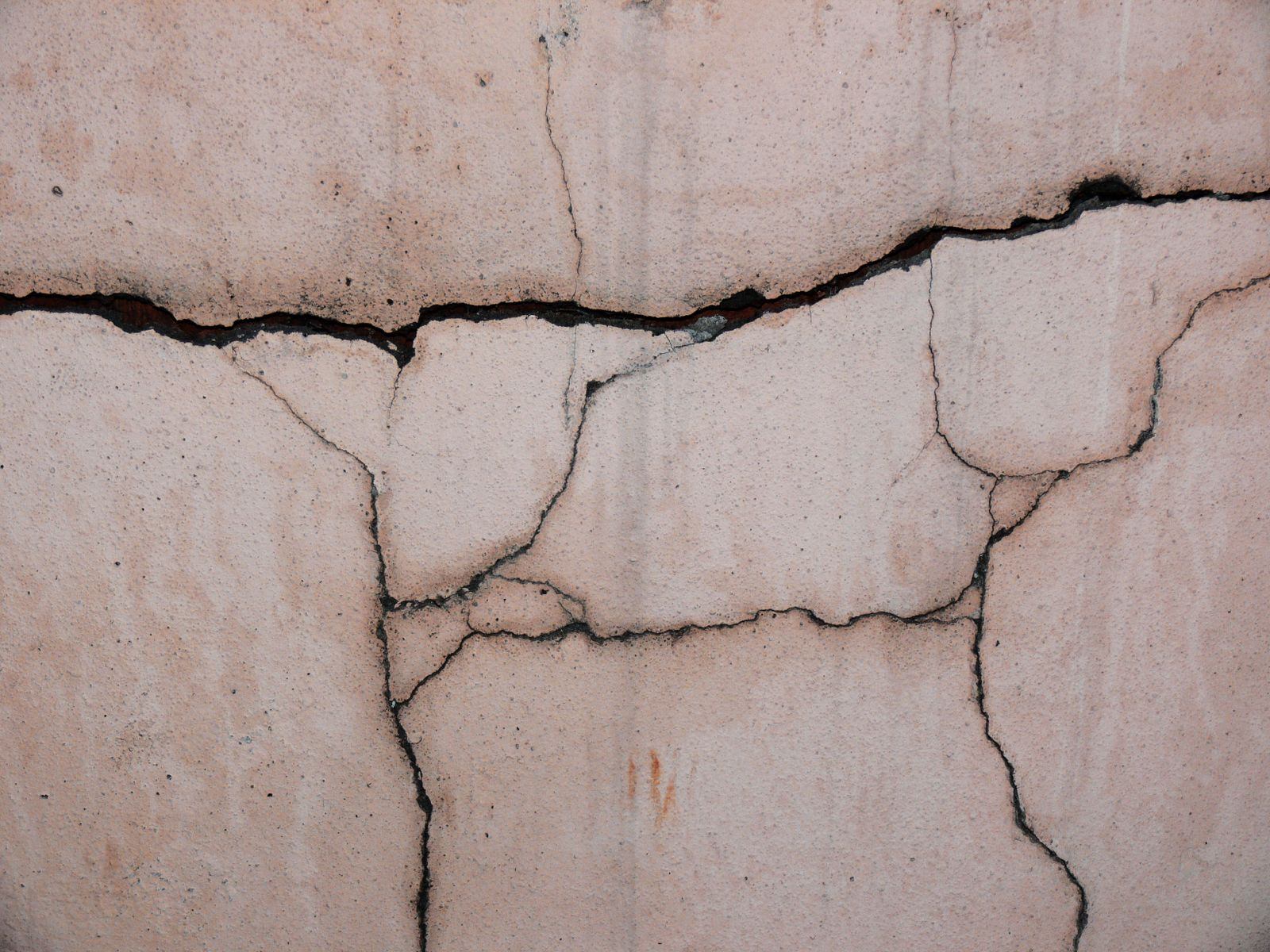 Concrete foundation wall with a wide branching crack running across it, the kind of structural crack clay soil movement opens up