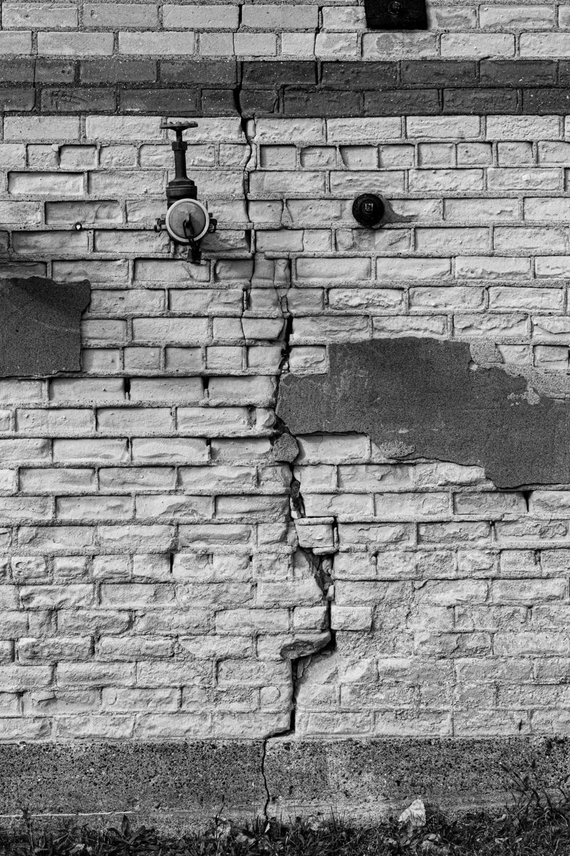 Stair-step crack climbing through the mortar joints of a brick wall, the classic exterior sign of a settling foundation